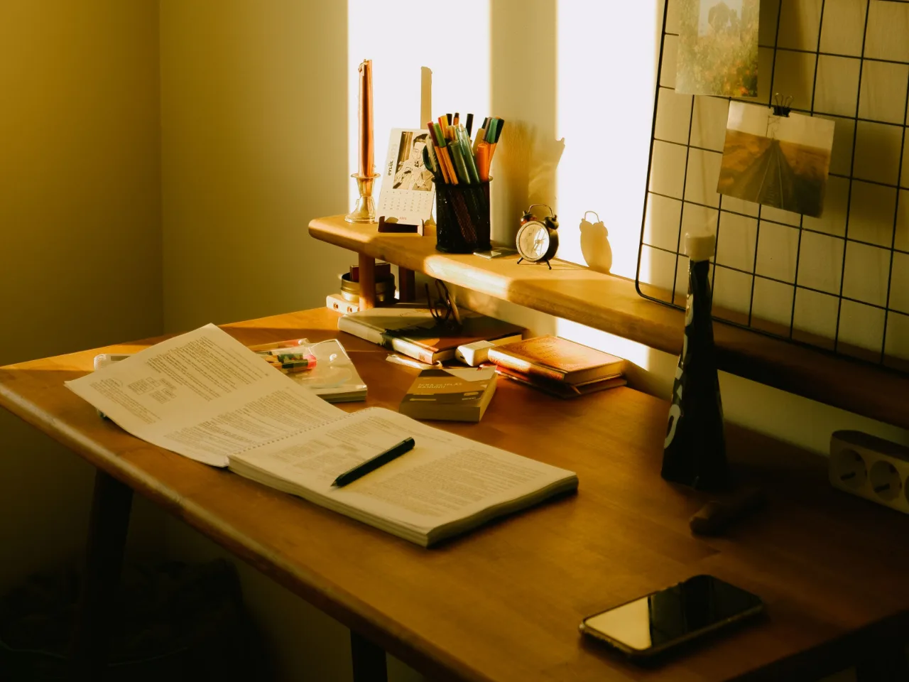 Une lampe de bureau allumee le soir, au-dessus de dossiers en ordre.